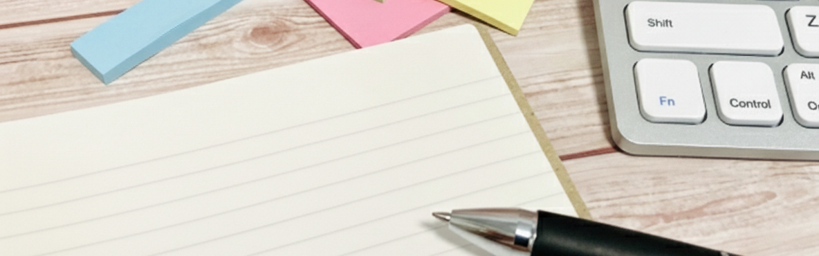 机の上に行政書士を連想させるペンと書類とキーボードが写った写真